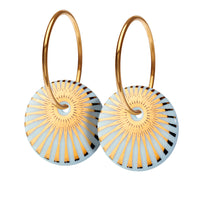 Øreringe med vedhæng af porcelæn, indfarvet i delikat lys blå, med SCHERNING's ikoniske SPLASH dekoration i blank guld. Forgyldt sterling sølv · Creol dia. 15 mm Vedhæng: håndlavet porcelæn · Dia. 14 mm Pris pr. par: 399 DKK CLOUD/GOLD · Varenr: SP14-3812G